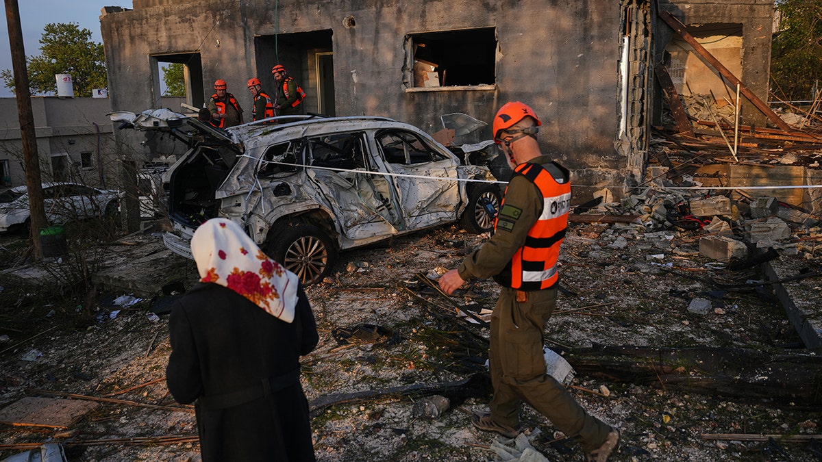 Residents and Home Front Command officers inspecting the interior of a heavily damaged residential home.